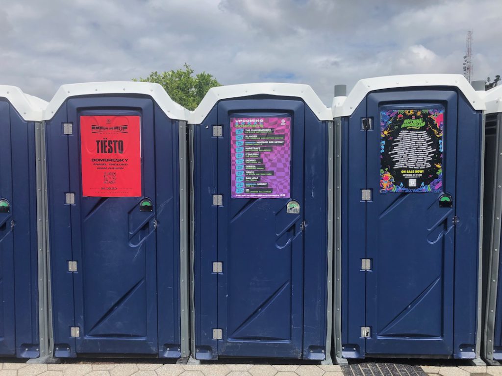 Port-a-potties covered with Insomniac posters at Los Angeles State Historic Park August 2023 Photo by Liz Ohanesian
