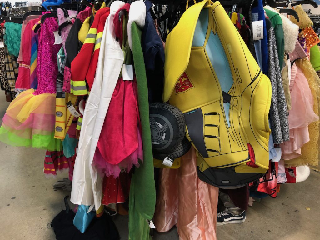 Halloween costume rack at Goodwill Glassell Park with brightly colored costumes for children including a Transformer costume and ballerina or princess outfits. (Photo: Liz Ohanesian)
