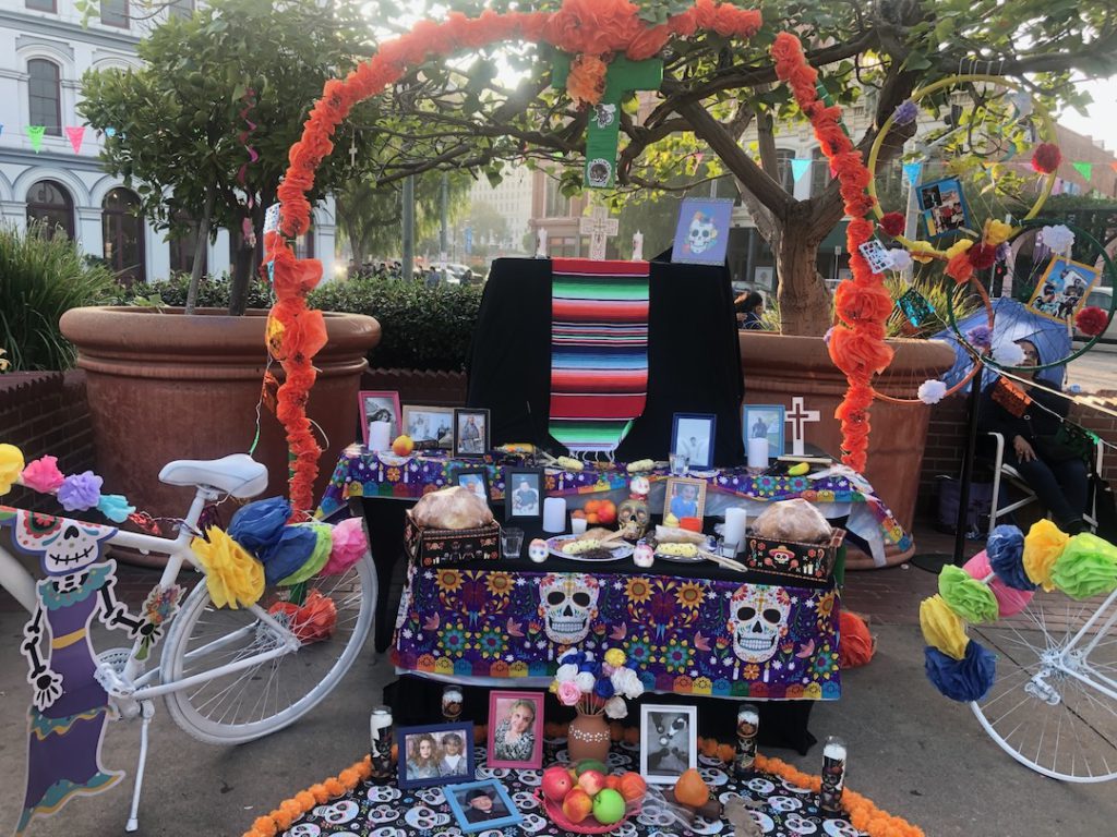 An altar for those who have passed in the cycling community at Olvera Street. Includes two bicycles as well as skeletons, flowers and photos (Photo: Liz Ohanesian)