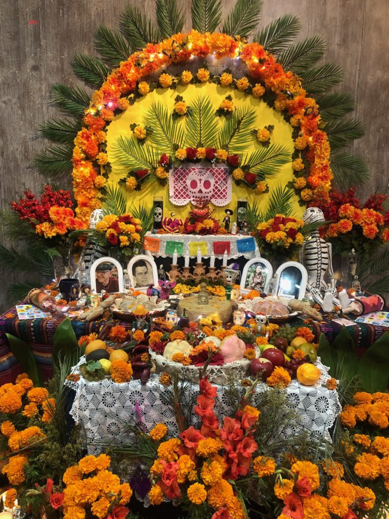 This altar by artists Margaret Chickie Beltran and Claire Sandoval is inside El Tranquilo on Olvera Street. It includes a variety of flowers, bread, fruit, sugar skulls and photos (Photo: Liz Ohanesian)