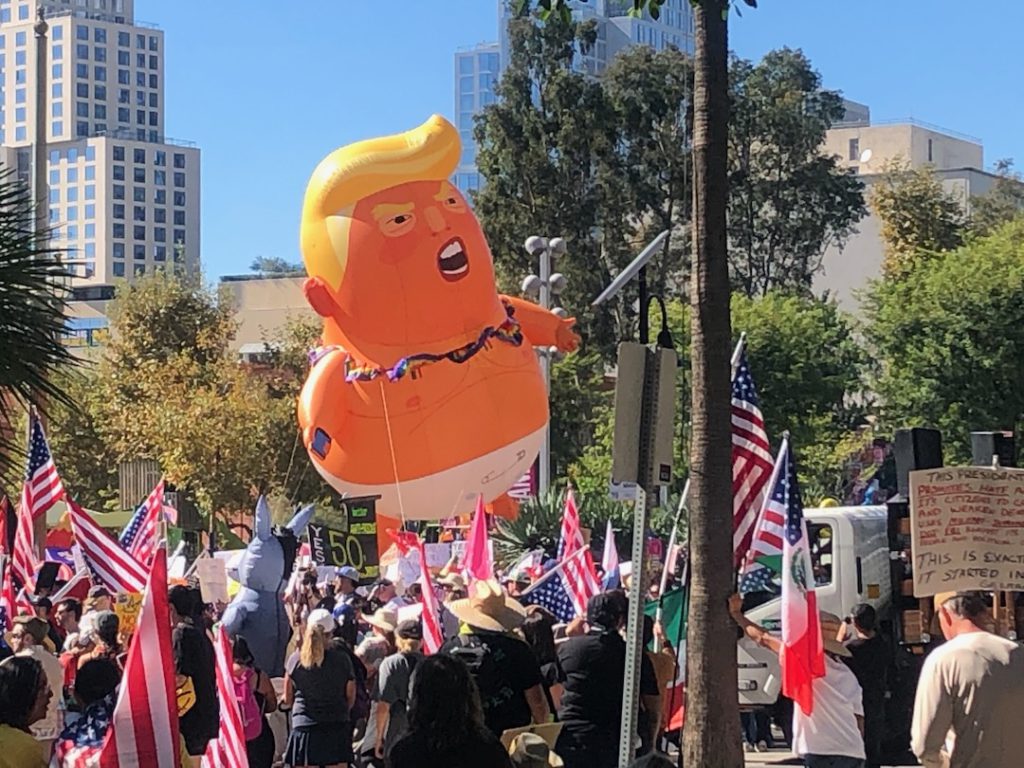 A balloon of Donald Trump as a scowling, oversized orange baby in a diaper floats over the crowd at No Kings events in downtown Los Angeles. October 18, 2025 (Photo: Liz Ohanesian)